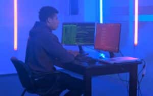 A guy is programing on PC using two monitors