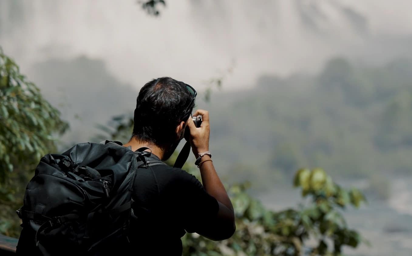 A guy is taking a photo of the waterfall