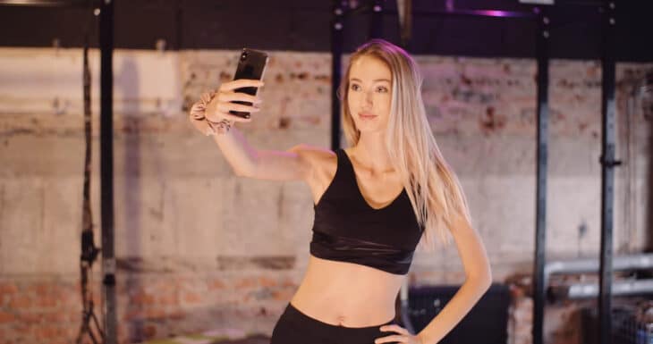 A female fitness influencer taking a photo in the gym