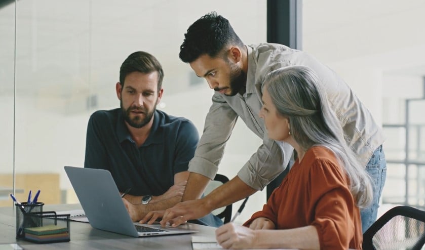 Focused team collaboration around a laptop