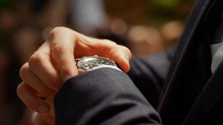 Underestimating time and financial investment shown by man checking his watch