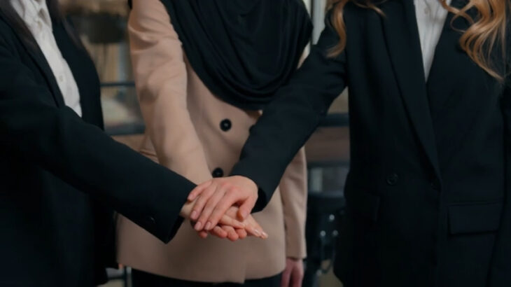 Group of businesswomen stacking hands in a show of unity and support, symbolizing teamwork and collaboration when starting a business