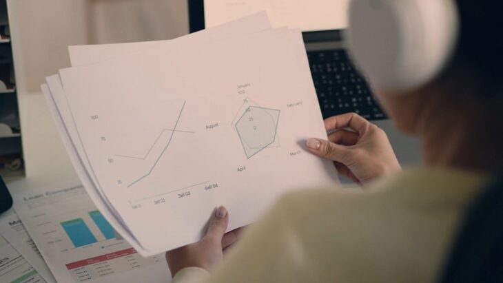 A person holding printed charts and graphs assessing risk management costs