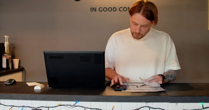 Male entrepreneur reviewing receipts and tracking customer data at a café counter