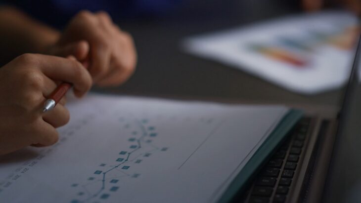 Close-up of hands holding a pen while reviewing data on risk recurrence charts