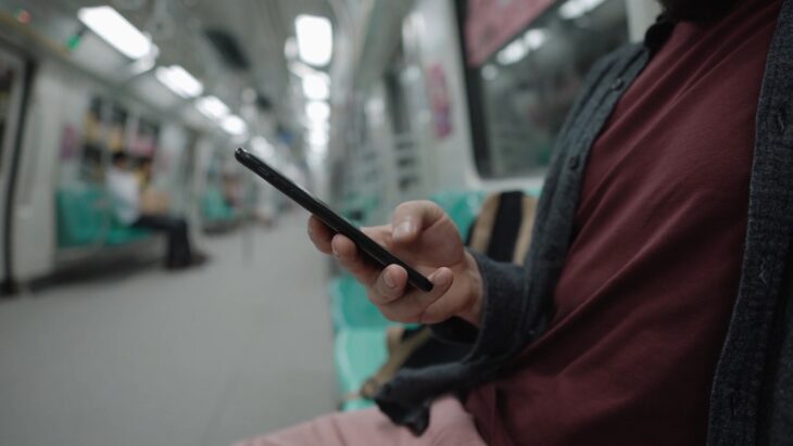 Man browsing on mobile while riding the subway, relying on mobile data in transit