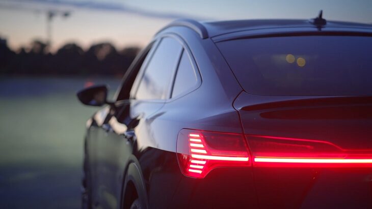 Rear view of a Tesla with red taillights glowing at dusk