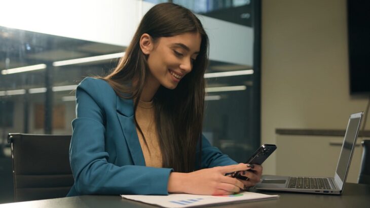 Businesswoman reviewing a Revenue Share Program on her phone in a modern