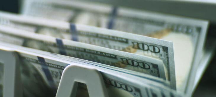 High-speed money counter processing stacks of $100 bills.