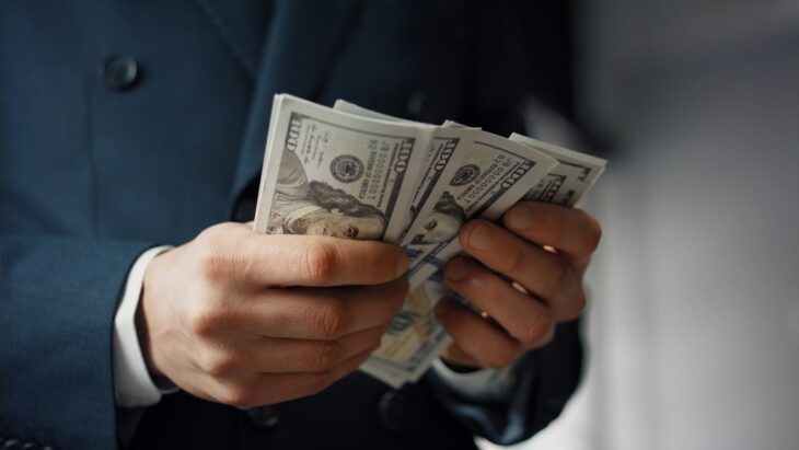 Businessman holding a stack of $100 bills in both hands