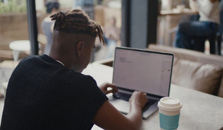 Freelancer typing on laptop in a café setting, .Many side hustles start with flexible freelance work in public spacesMany side hustles start with flexible freelance work in public spaces