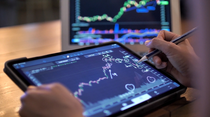 A person analyzing and marking financial charts on a tablet as part of upgrading a finance toolkit