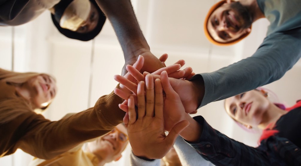 Close-up view of hands clasped together, highlighting the shared effort and support within a group