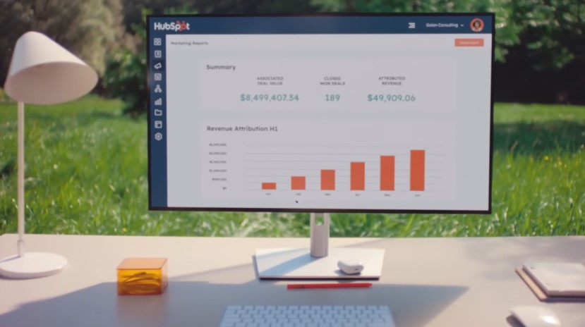 A modern workspace displays a HubSpot dashboard, showcasing revenue attribution for Q1