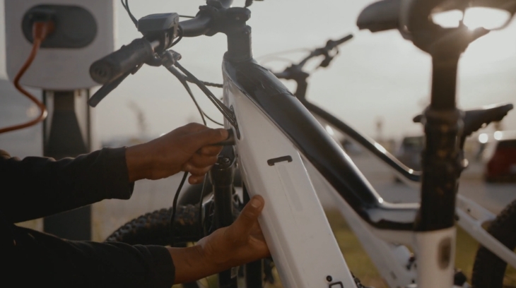 Person plugging in an electric bike at a charging station for EV charging infrastructure
