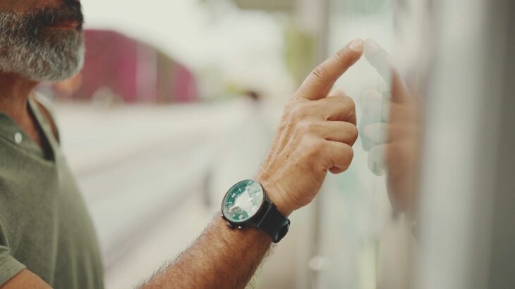Older man pointing at a public timetable, highlighting decisions about material spending or time spending