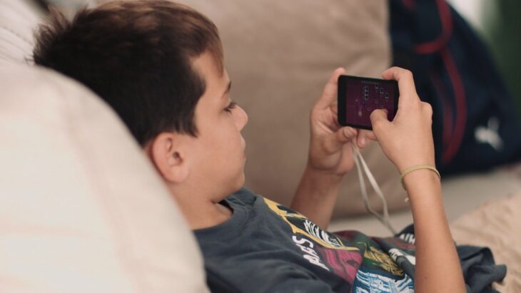 Boy lying on a couch playing a competitive mobile game, reflecting mobile esports on the rise