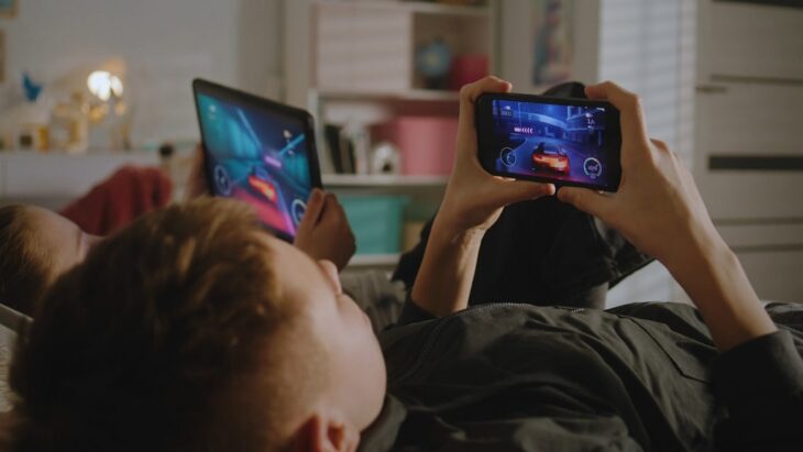 Two kids playing racing games on tablet and smartphone, highlighting smarter monetization models in mobile games