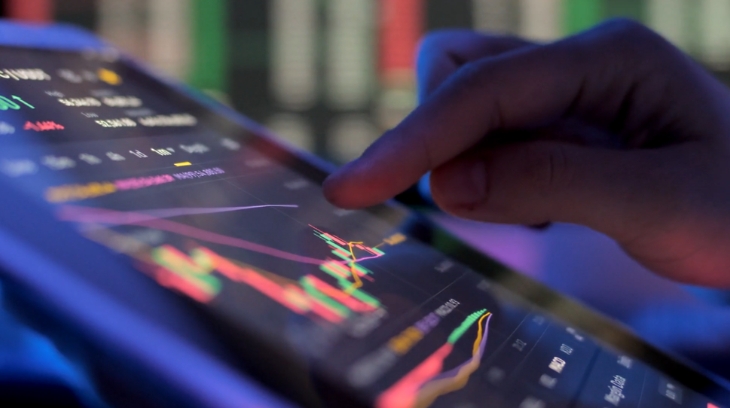 A person analyzing colorful financial graphs and charts on a digital tablet during market tracking