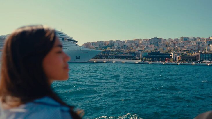 Woman looking at a cruise ship from the shore, symbolizing travel planning and upcoming journeys