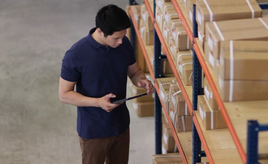 Warehouse worker meticulously reviewing inventory on a tablet