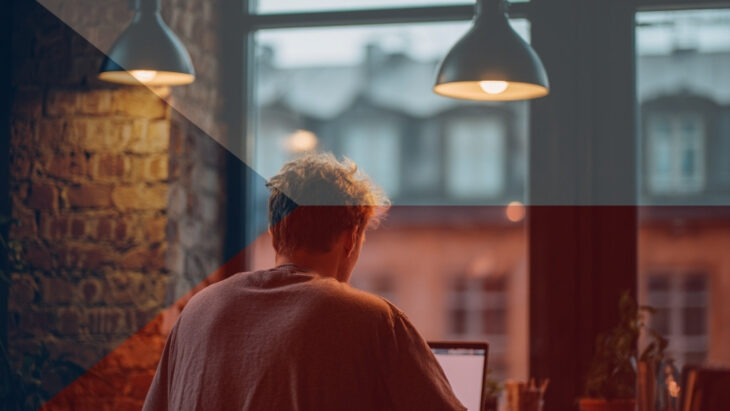 Male freelancer in a Prague coworking space, working on a laptop in a modern loft-style interior