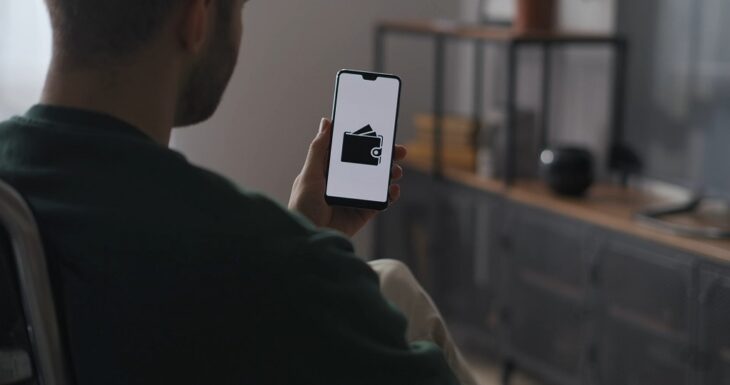Man holding smartphone displaying a digital wallet icon, representing convenient mobile payment and modern online transaction options
