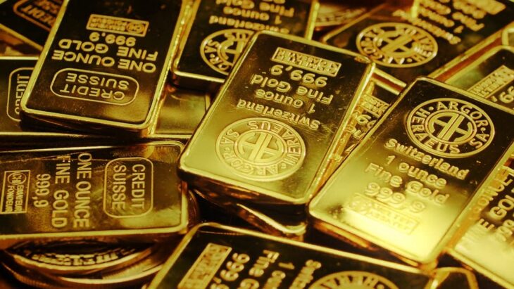 A close-up view of stacked one-ounce gold bars, stamped with purity marks and minting information