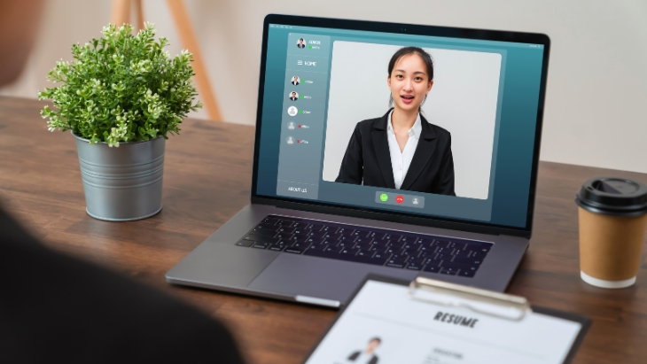A candidate appears on a laptop screen presenting a video resume during an interview