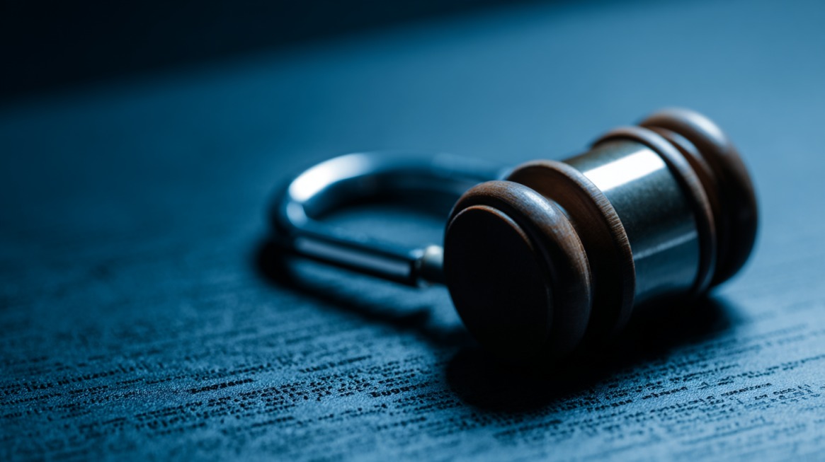 Close-up of a gavel resting beside an unlocked padlock on a desk