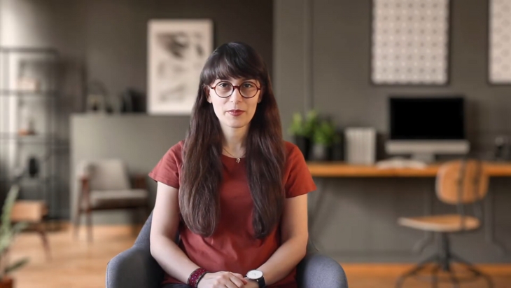 A woman sits in a modern office space recording a video resume