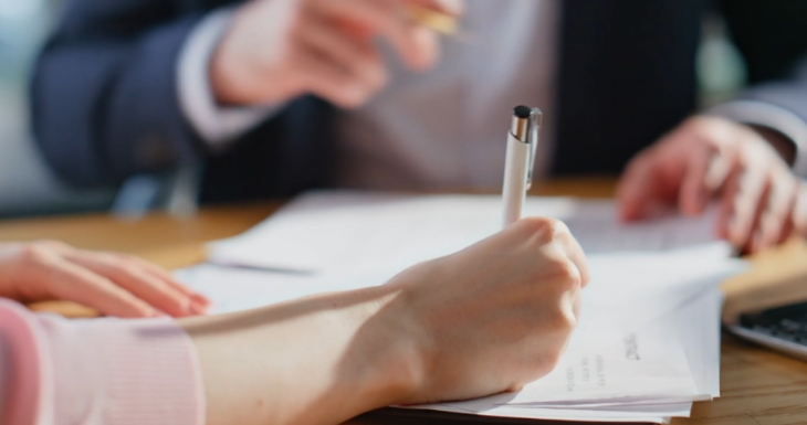 A person signs documents during a discussion about company policies