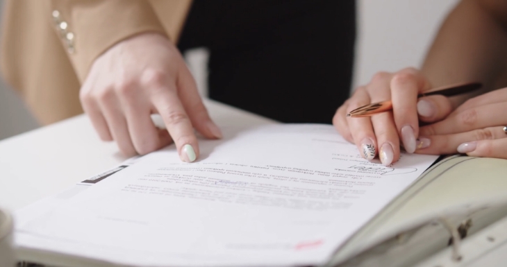 Hands review and sign paperwork on a desk for legal protection