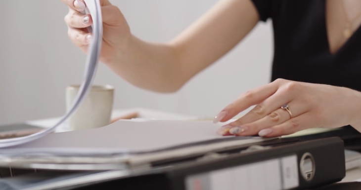 A person reviews documents in a binder for incident reporting and risk assessments