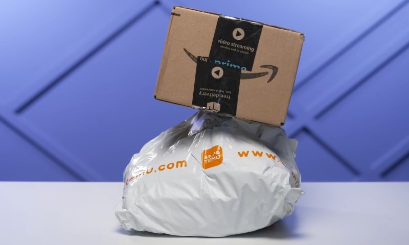 A small Amazon package balances atop a crumpled Temu shipping bag against a blue background