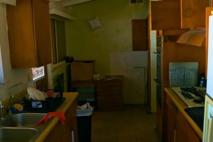 Narrow, outdated kitchen with old cabinets, appliances, and limited lighting