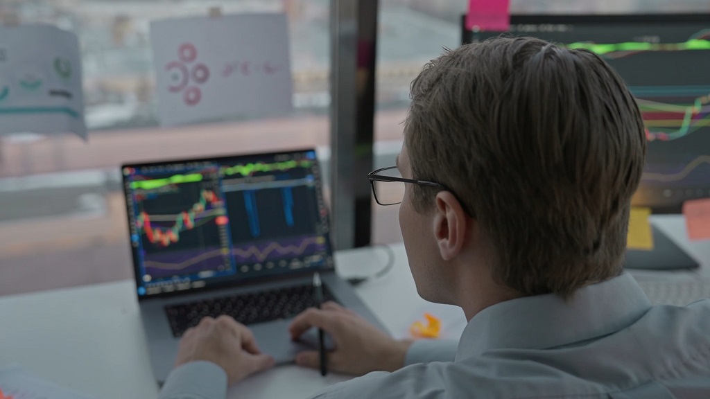 Trader reviewing stock market charts and technical indicators on a laptop trading interface