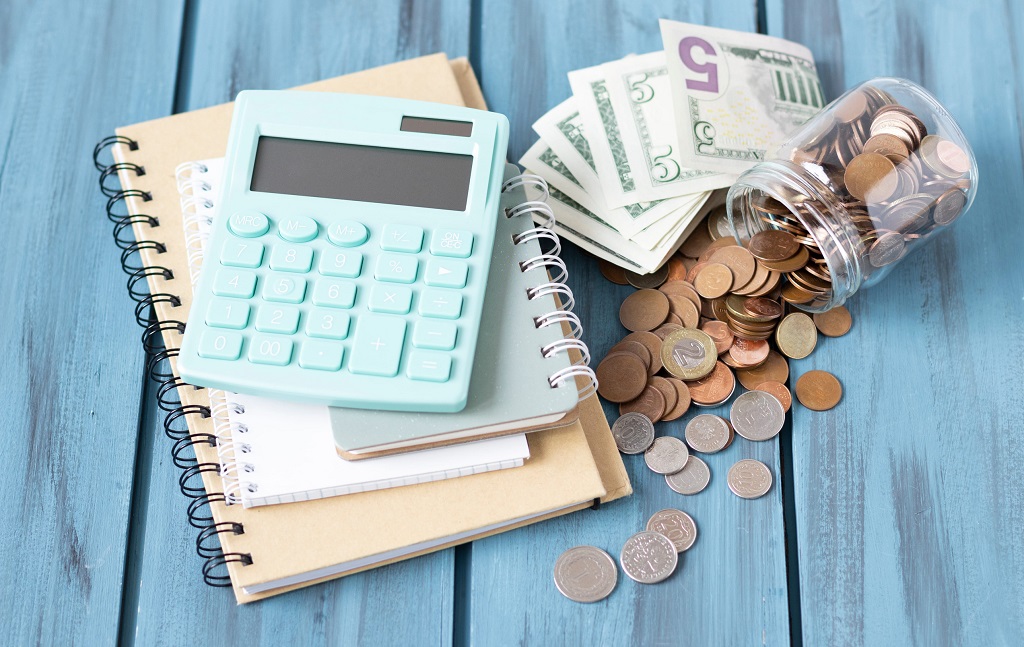 Money, coins, calculator and some stationery on wood table, top view with copy space - financial background concept